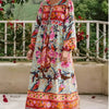 Una mujer modela un largo vestido maxi floral con bordados y borlas de colores al aire libre.