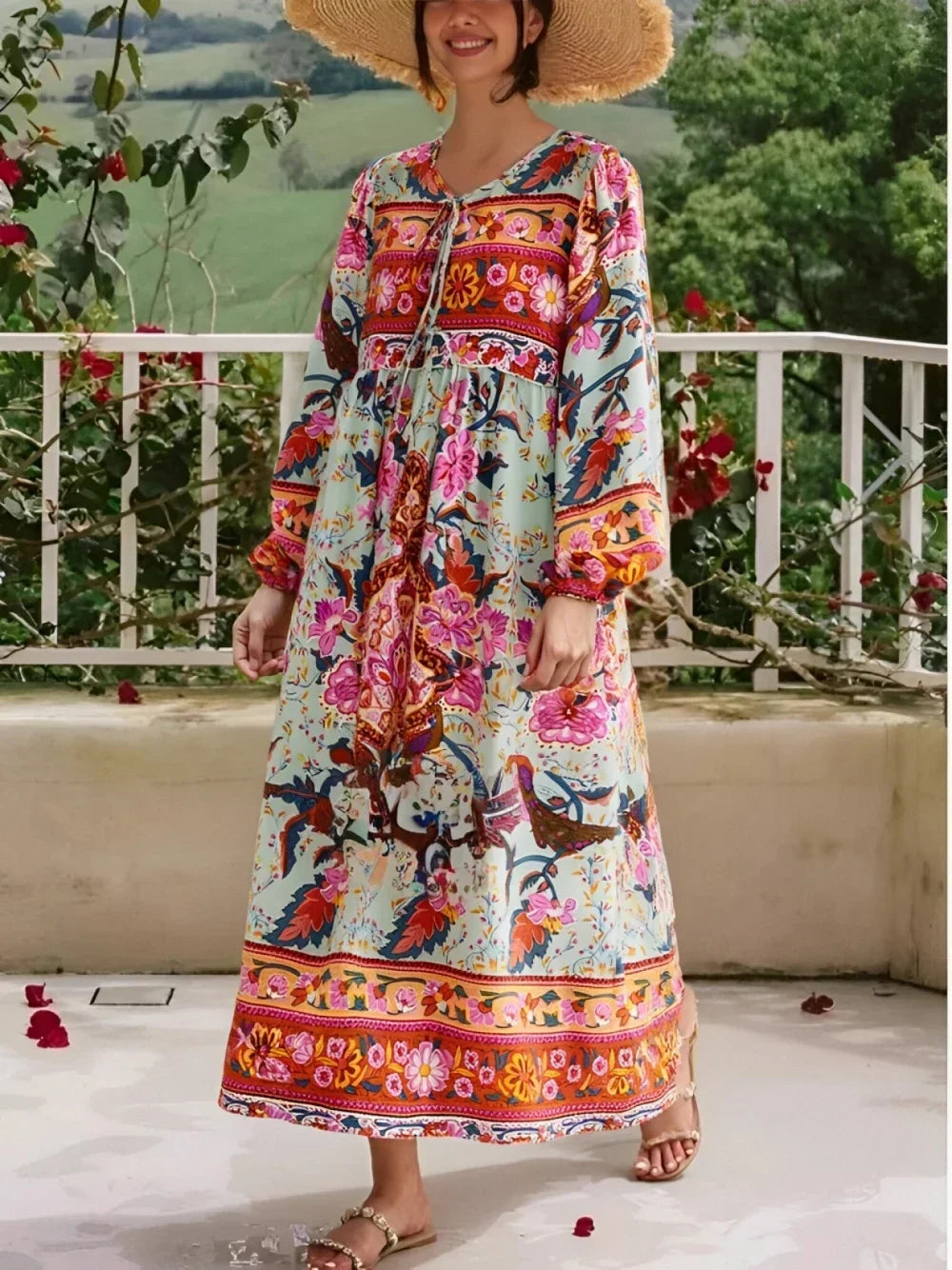Una mujer modela un largo vestido maxi floral con bordados y borlas de colores al aire libre.