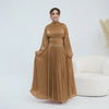 Une femme portant une abaya bronze fluide avec ceinture ornée.