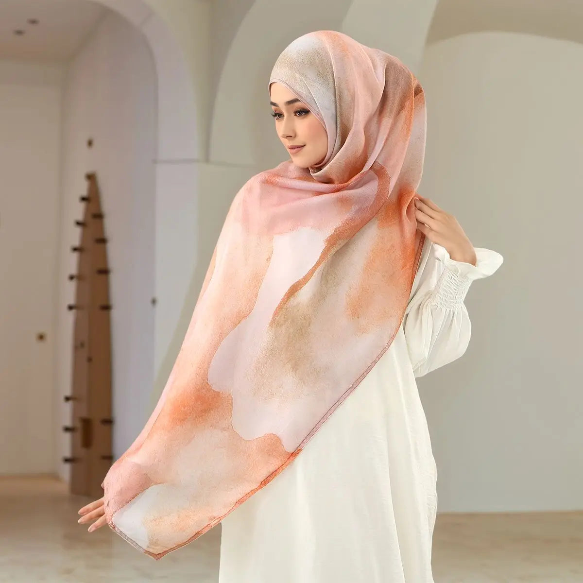 Eine Frau trägt einen eleganten bedruckten Baumwoll-Rayon-Hijab-Schal in sanftem Pfirsich- und Weißton.