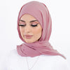 Une femme portant un hijab en mousseline rose poudré et un haut blanc.