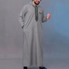 A man wearing a grey Moroccan ethnic thobe with a stand collar and embroidery.