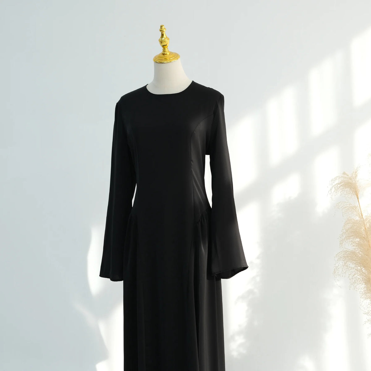 Abaya elegante de manga larga negra mostrada en maniquí.