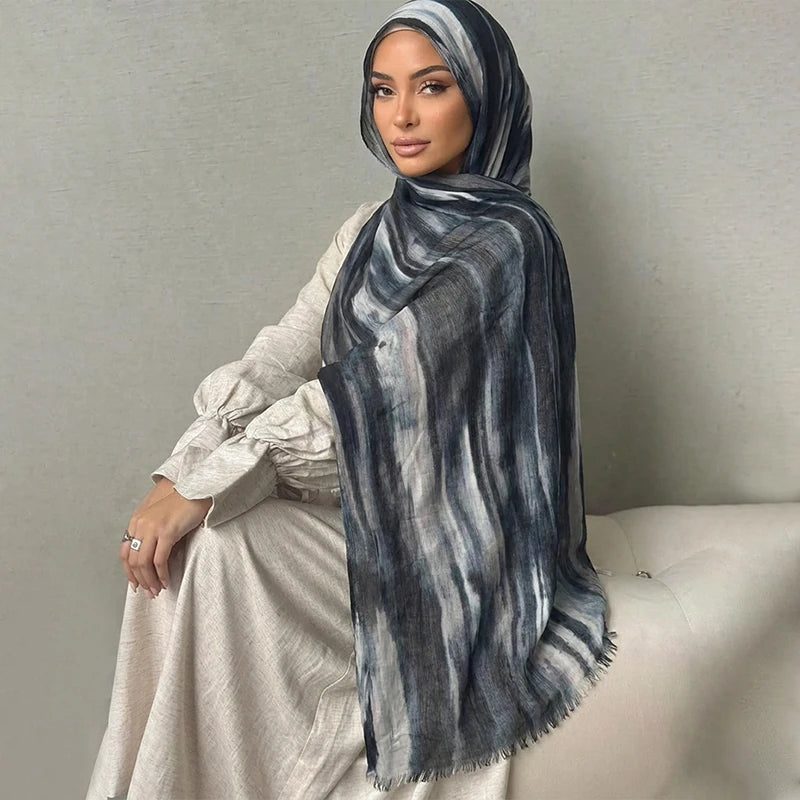 Una mujer vistiendo un pañuelo hijab de acuarela floral bohemio a rayas grises y blancas y un vestido beige claro.