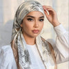 A woman wearing an elegant satin silk instant hijab scarf with floral embroidery and a white top.