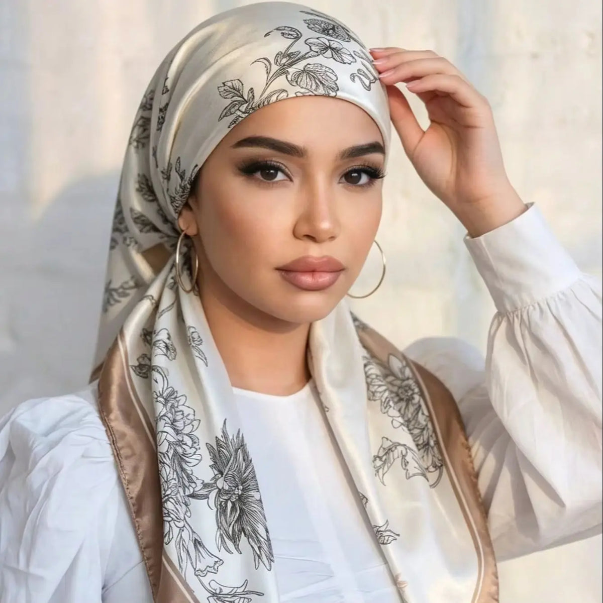 A woman wearing an elegant satin silk instant hijab scarf with floral embroidery and a white top.