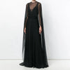 A woman wearing an elegant sheer mesh poncho cape dress in black for evening wear.