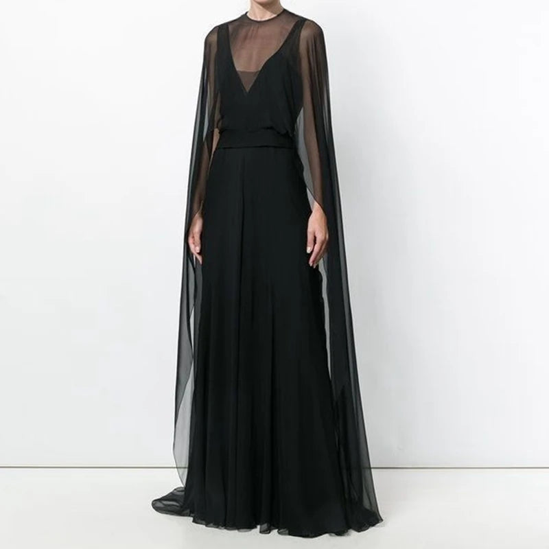 A woman wearing an elegant sheer mesh poncho cape dress in black for evening wear.