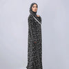 A woman wearing an elegant black and white patterned Muslim hijab dress for daily wear.