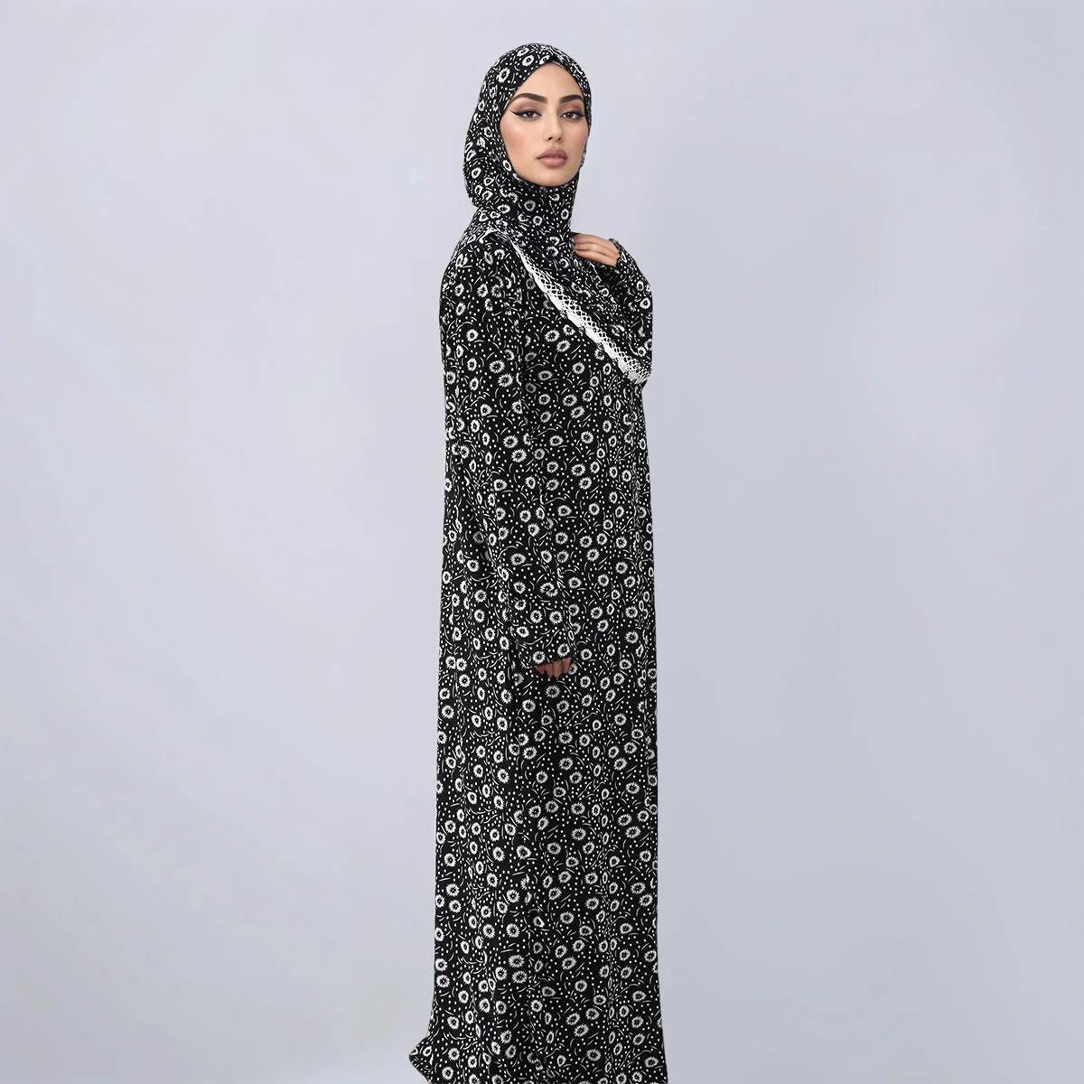 A woman wearing an elegant black and white patterned Muslim hijab dress for daily wear.