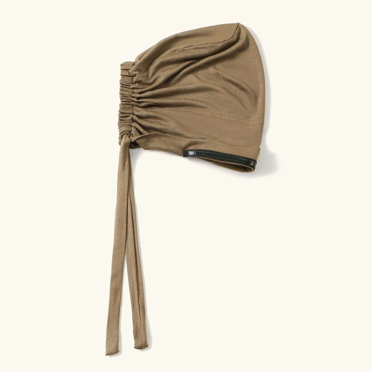 A beige anti-slip inner hijab cap with a gathered fabric top and a black trim detail.