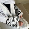 Une femme portant une abaya blanche avec broderie noire et dentelle sur les manches.