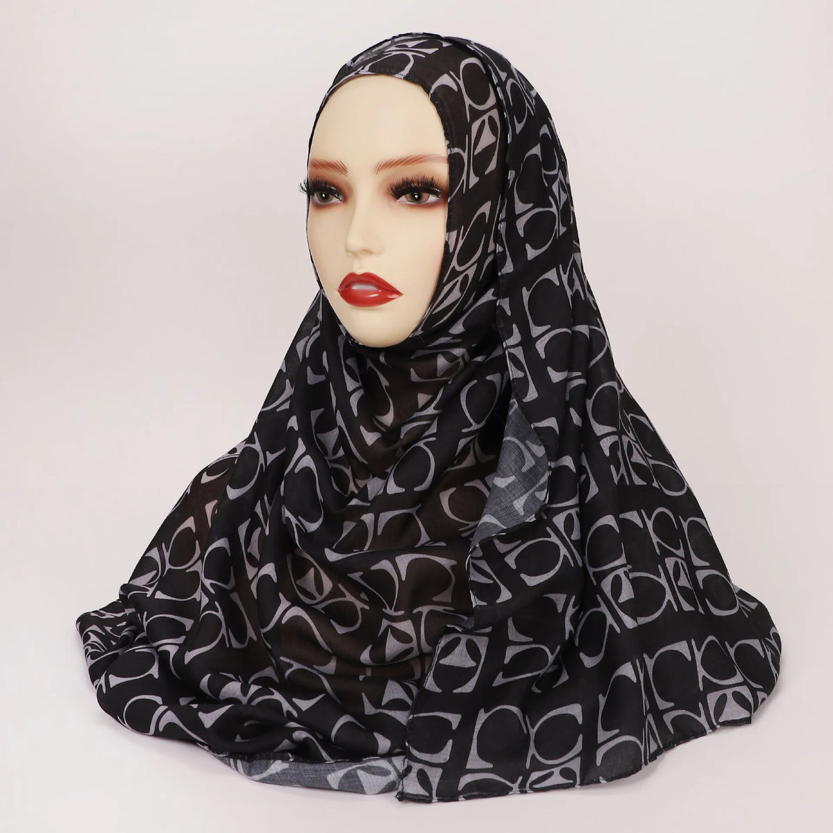 Un pañuelo de hijab negro con estampado de leopardo mostrado en un maniquí de cabeza.
