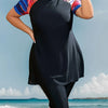 Eine Frau in einem schwarz gemusterten Maxi-Tankini-Bikinianzug steht draußen in der Nähe des Ozeans.