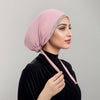 Eine Frau trägt einen pudrigen Rosé-Strass-Hijab und ein schwarzes Samt-Oberteil.