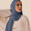 A woman wearing a solid blue soft modal jersey hijab scarf with a light beige top.