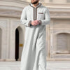 A man wearing a light beige Moroccan embroidered thobe jellaba with gold detailing.
