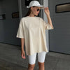 Una mujer vistiendo una camiseta básica oversize color crema y pantalones blancos, mirando hacia un lado.