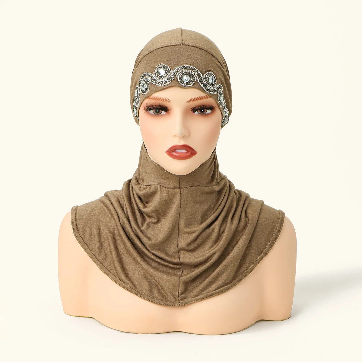 Una modelo vistiendo un pañuelo beige con bordado plateado y una tela a juego.