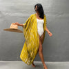 Eine Frau trägt ein gelb gemustertes Kimono-Überkleid über ein weißes Kleid und hält einen Strohhut.