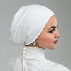 Primer plano de una mujer vistiendo un gorro de hijab interior de jersey blanco elástico con pendientes de perla.
