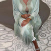 Una mujer vistiendo un elegante vestido kaftan verde menta con intrincados bordados de perlas y tela fluida.