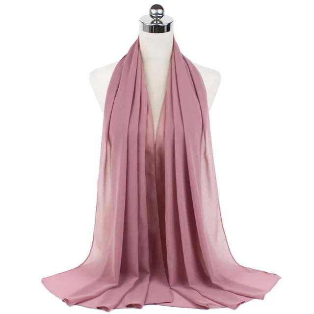 A soft dusty rose chiffon hijab scarf draped around a mannequin's neck.