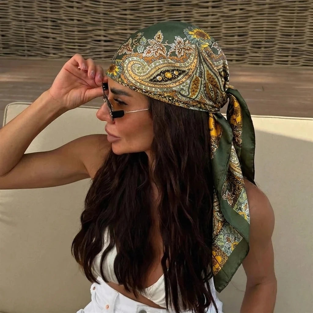 A woman wearing an elegant silk dot print scarf tied around her hair and neck.
