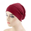 Un mannequin porte un foulard élastique rouge foncé sur la tête.