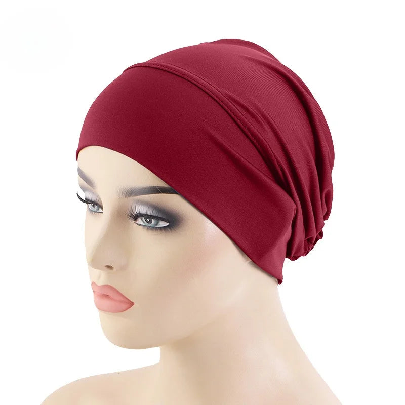 Un mannequin porte un foulard élastique rouge foncé sur la tête.