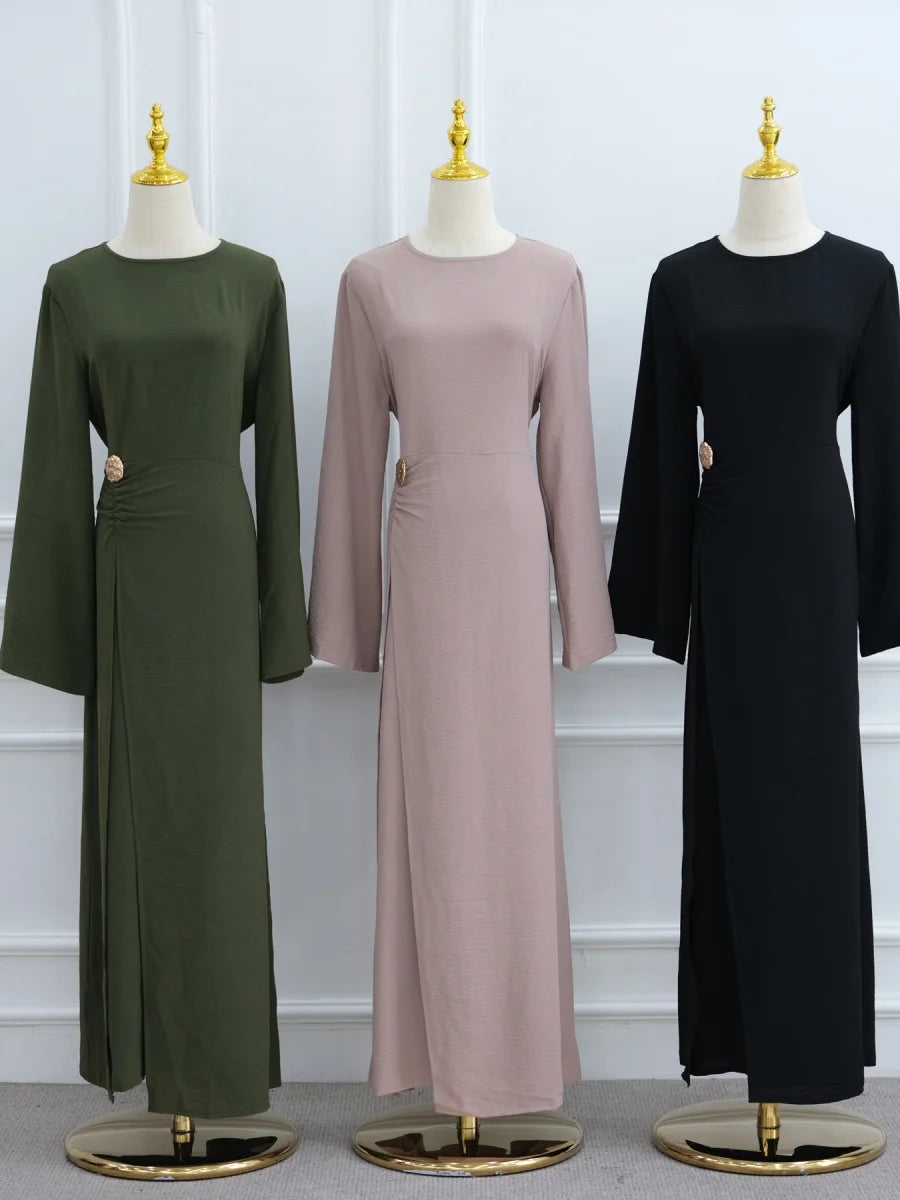 Trois abayas élégantes à cordon pour femmes, vert olive, mauve et noir, présentées sur des mannequins.