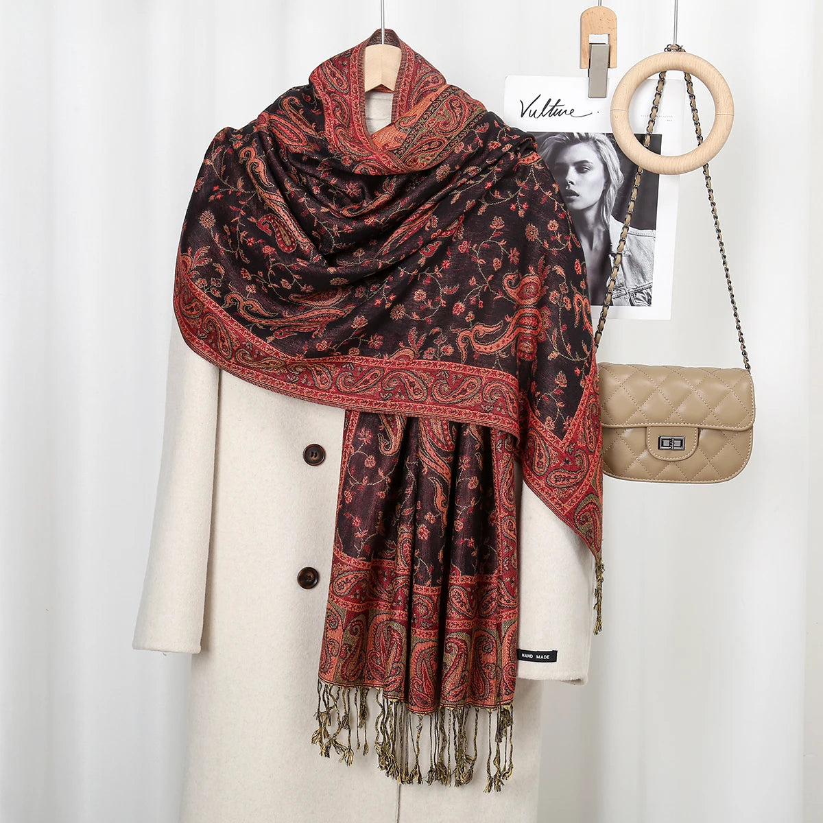 Dunkelbraunes und rostfarbenes Paisley-Viskosertuch über einem cremefarbenen Blazer, mit zur Ausstellung angebrachten Holzrin