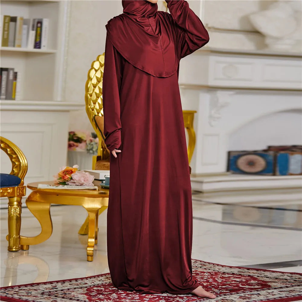 Una mujer vistiendo una túnica de abaya kaftan islámica larga color granate en un entorno formal.