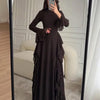 A woman models an elegant black high-waisted long-sleeve A-line maxi dress in a full-length mirror.