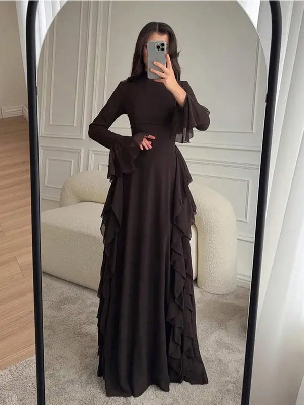 A woman models an elegant black high-waisted long-sleeve A-line maxi dress in a full-length mirror.