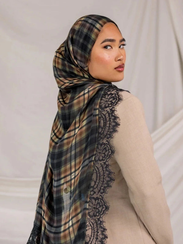 A woman wearing a plaid hijab scarf with black lace trim and a beige top.