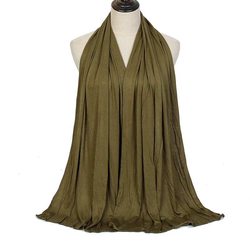 A woman wearing a olive green soft modal jersey hijab scarf draped in a cowl neck style.