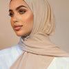 Una mujer vistiendo un hiyab instantáneo beige y ropa blanca.
