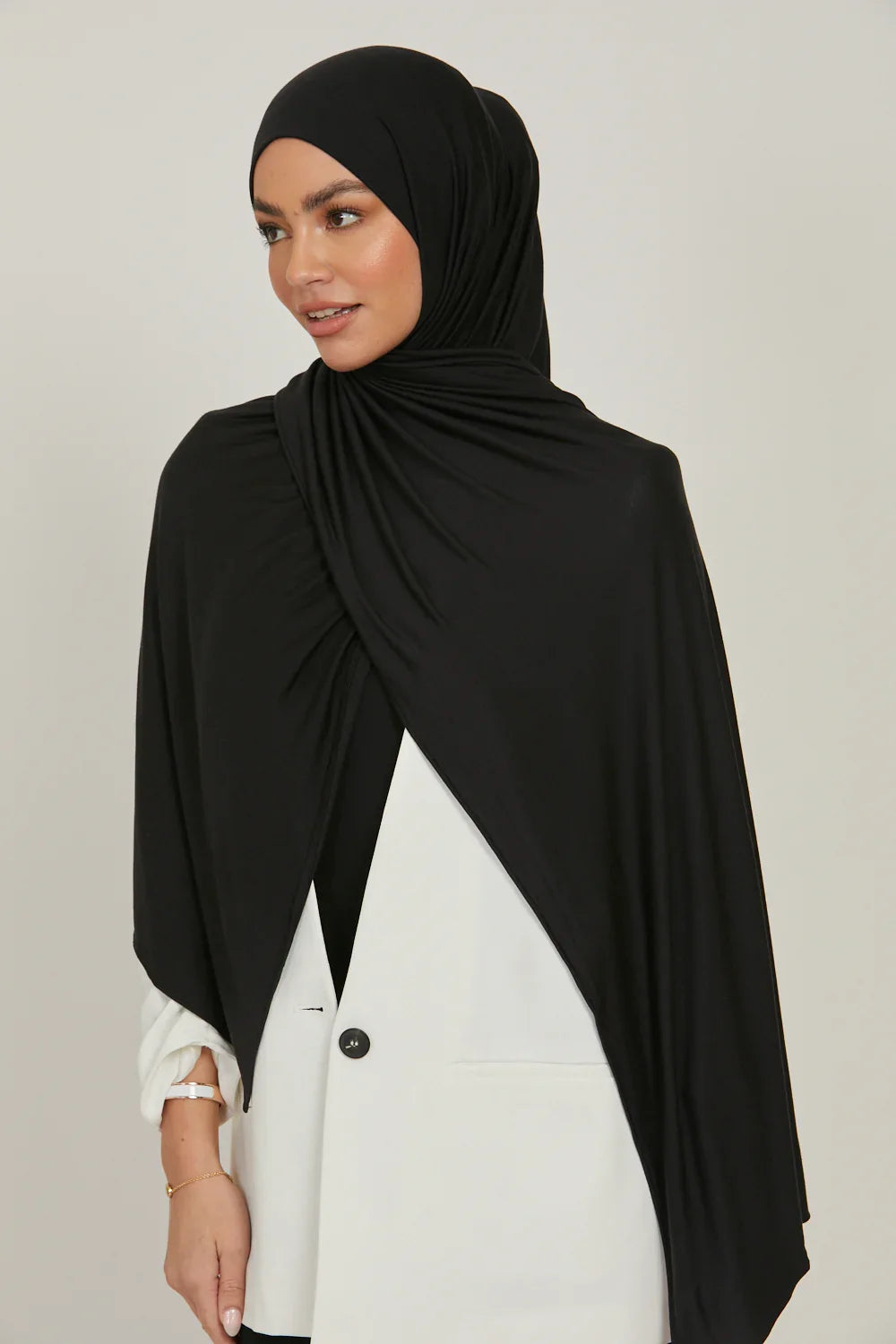 Eine Frau trägt einen schwarzen Jersey-Hijab und ein weißes Oberteil.