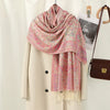 Chal de bordado paisley rosa y crema sobre un abrigo beige.