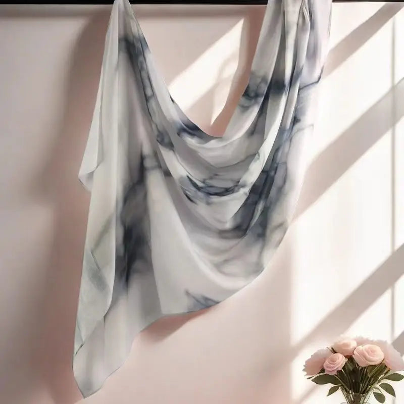Fließender weiß-grauer Aquarell-Blumenmuster-Schal, über eine Wand drapiert.