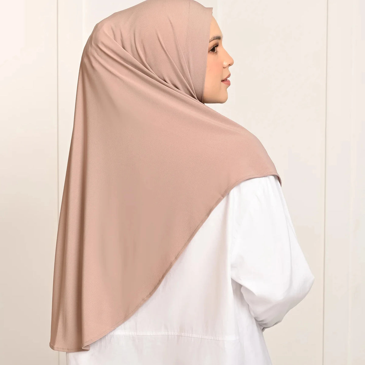 Une femme portant un foulard turban en coton de chanvre beige par-dessus une tenue blanche.