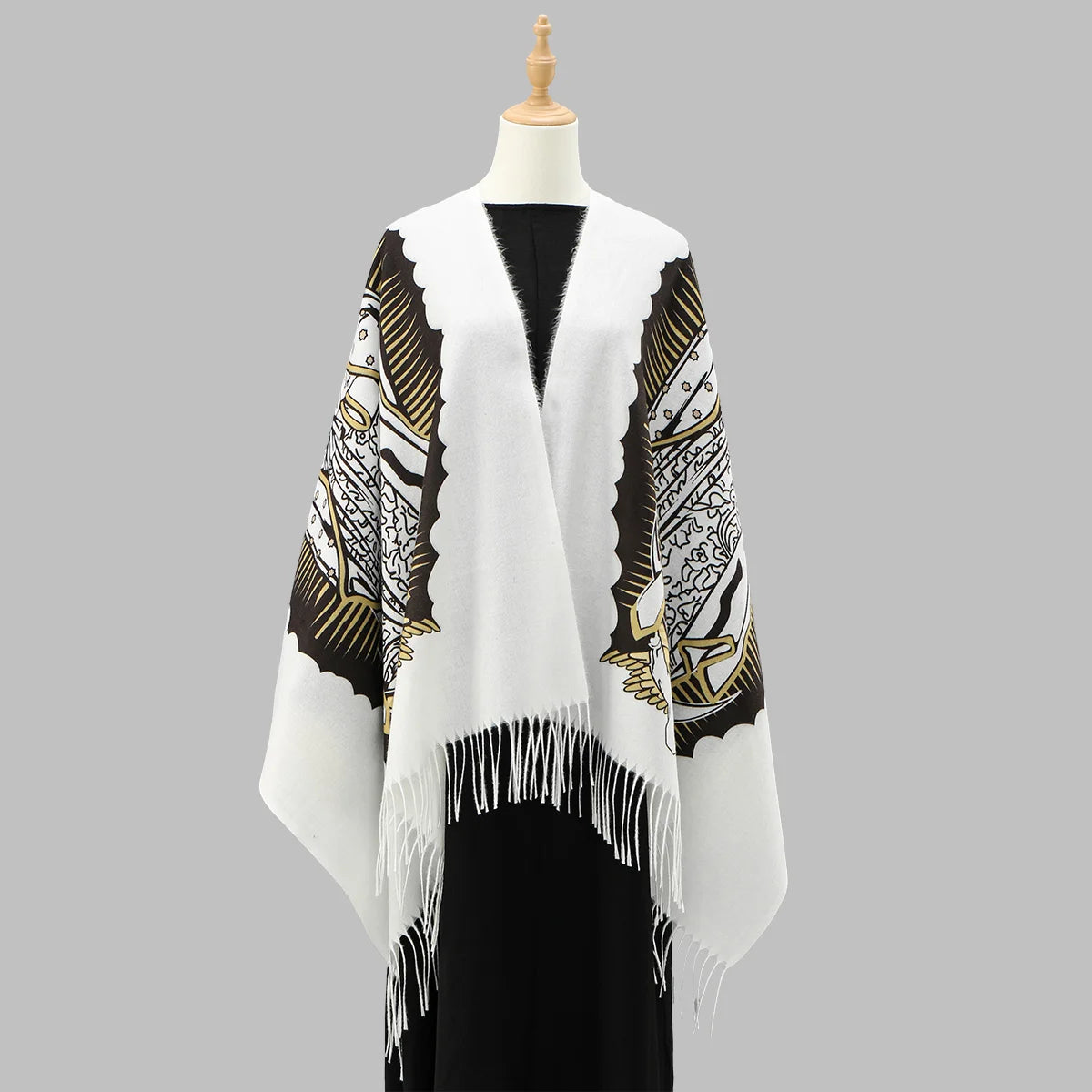 Weißer Schal mit schwarz-goldenen Mustern und Fransen auf einem Mannequin.