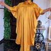 Eine Frau trägt eine fließende goldgelbe Kaftan-Abaya für Abendkleidung in einem Raum.