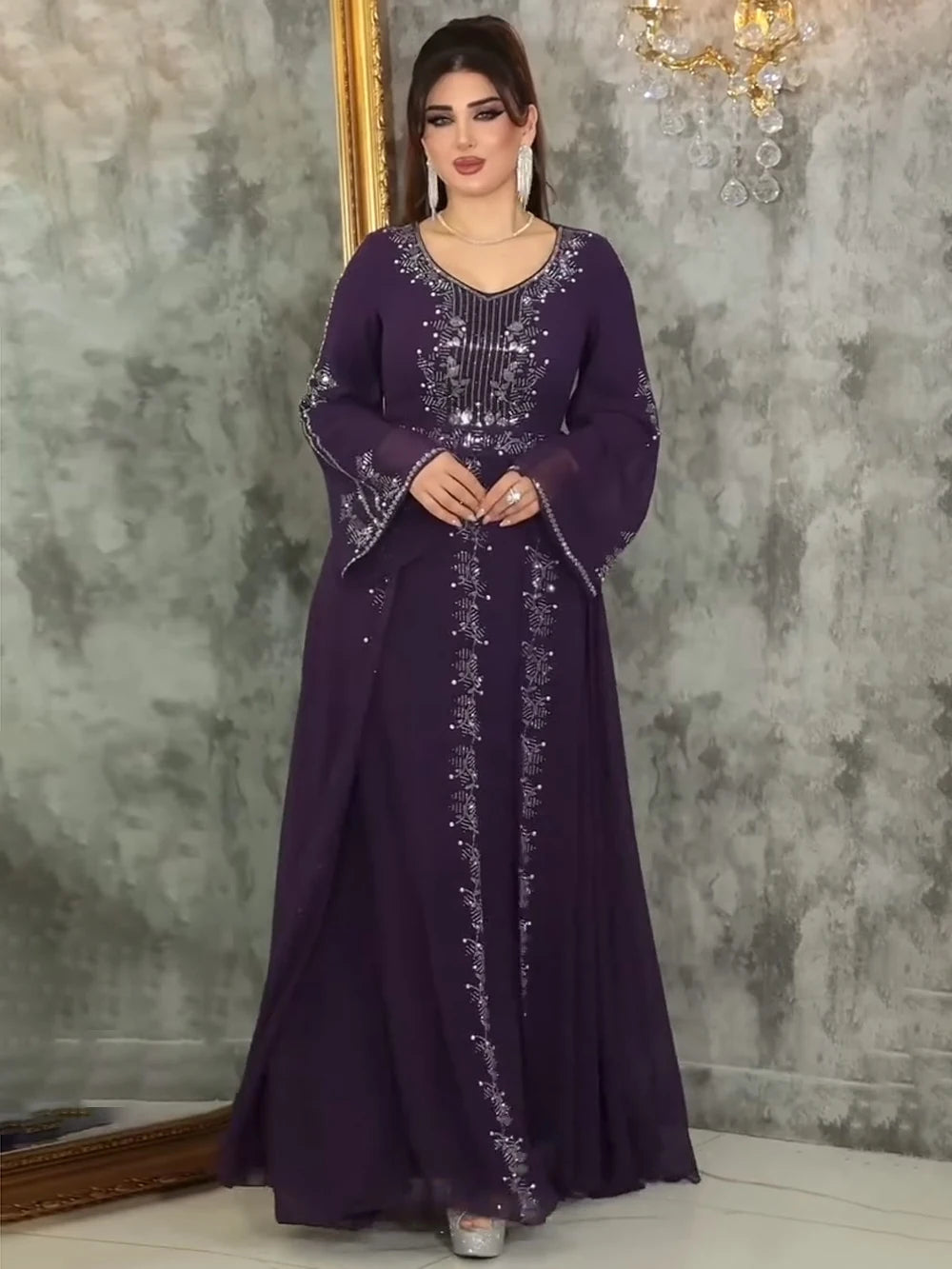 Eine Frau trägt ein elegantes lila Chiffon-Abaya-Kleid mit Rüschenärmeln und silbernen Verzierungen.
