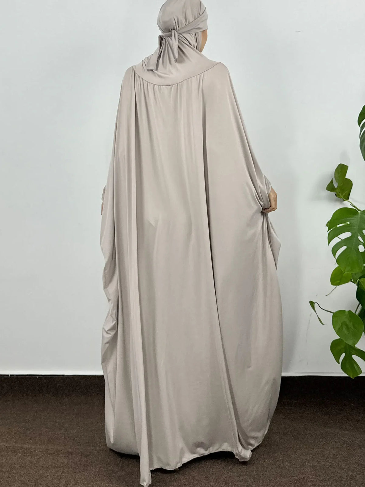 Una mujer vistiendo una elegante y fluida abaya beige clara con capucha para el Ramadán.