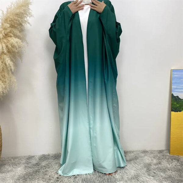 An elegant teal green flowing cardigan robe worn by a person against a white wall.