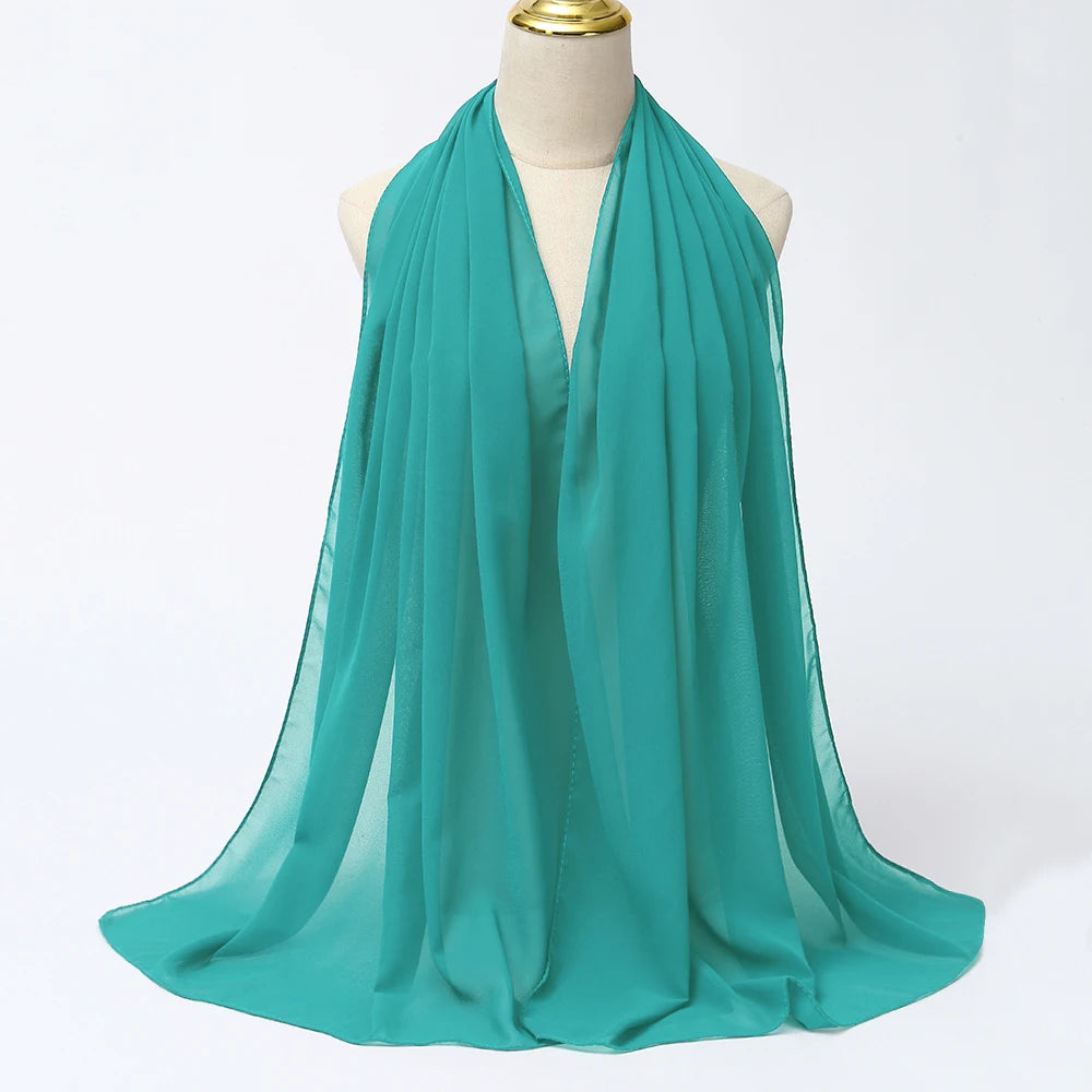 Ein tealfarbener Chiffon-Hijab-Schal, drapiert um den Hals und die Schultern einer Mannequin.