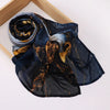 Voile hijab imprimé bleu foncé avec motifs abstraits or et brun, drapé sur un cadre en bois.