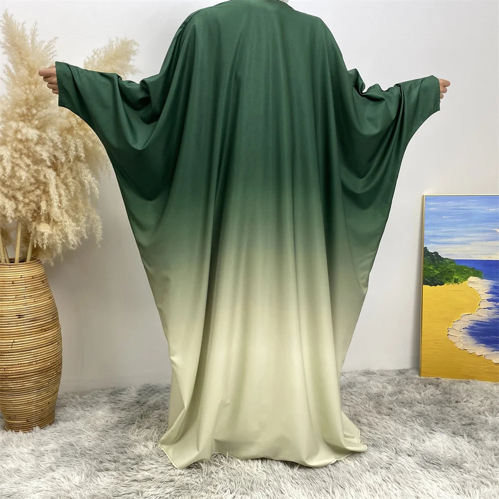 Robe islámica fluida verde esmeralda y amarillo pálido sobre fondo blanco.